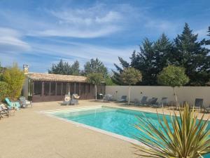- une piscine dans une cour entourée de chaises dans l'établissement Les Bergeries de Saumane, gîte 6 personnes au sein d'un ensemble de 4 gîtes,Piscine commune, à Saumane-de-Vaucluse