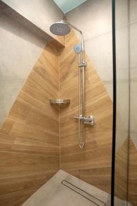 een douche met een houten wand en een douchekop bij The Frogs_Guest House in Athene