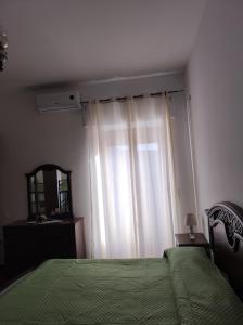 ein Schlafzimmer mit einem Bett mit einer grünen Decke und einem Fenster in der Unterkunft Bettyhouse casa vacanza in Cariati