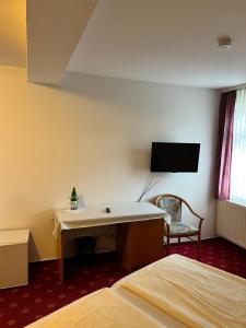 a hotel room with a desk and a tv on the wall at Hotel Schwartzer Löwe in Babenhausen