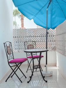 a table and two chairs under a blue umbrella at Your Airport Oasis Resort 15 Minutes from Rabat in Salé