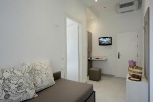 a white living room with a couch and a tv at Hotel Aurora in Misano Adriatico