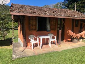 een tafel en stoelen buiten een klein huis bij Pousada Mariza in Nova Friburgo