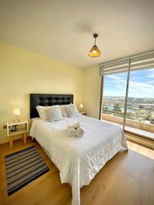 1 dormitorio con cama blanca y ventana grande en Laguna Redonda · Hermoso Departamento con Espectaculares Vistas, en Concepción