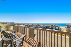 a deck with two chairs and the ocean at Cape Escape in Pacific City