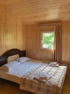 een bed in een houten kamer met een raam bij Hotel Okatsia სასტუმრო ოკაცია in Gordi