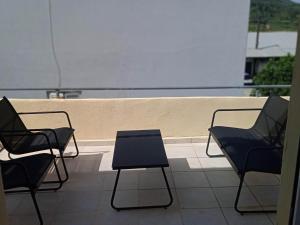 three chairs and a table on a balcony at Popi's Apartment in Goníai