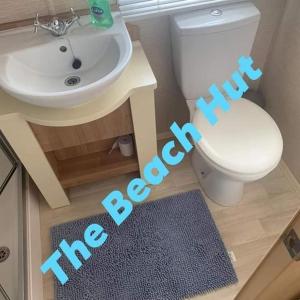 a bathroom with a white toilet and a sink at The Beach Hut on Lyons Winkups Holiday Park in Kinmel Bay
