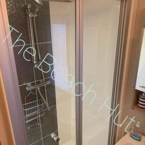 a shower with a glass door with writing on it at The Beach Hut on Lyons Winkups Holiday Park in Kinmel Bay