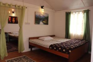 a bedroom with a bed and a window with green curtains at K - Den Homestay & Cafe in Kurseong