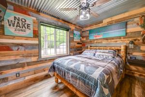 ein Schlafzimmer mit einem Bett in einem Zimmer mit Holzwänden in der Unterkunft Lakeside Cabin with Fire Pit Near Pine Point Park! in Holcombe
