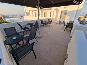 een balkon met stoelen en tafels en een parasol bij Aerial Apartment in Karterados