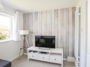 a living room with a television on a white cabinet at Bryn Llifon in Pentraeth