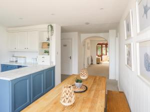 a kitchen with blue cabinets and a wooden table at Bryn Llifon in Pentraeth