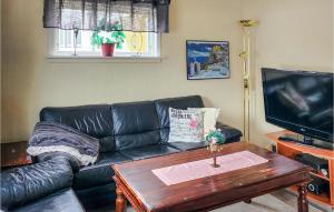 Sala de estar con sofá de cuero negro y mesa de centro en Amazing Home In Fjordgard With Wifi, en Fjordgård