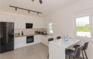 una cucina con armadi bianchi, tavolo e sedie di Awesome Home In Bilice With Wifi a Bilice (Bilizze)