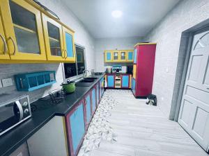a kitchen with yellow and red cabinets and a tile floor at La maison bleue in Sada +1 photo