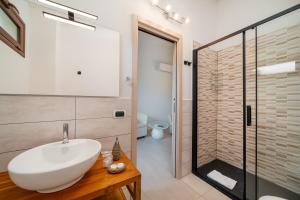 La salle de bains est pourvue d'un lavabo blanc et d'une douche. dans l'établissement Rooms Tavolara, à San Teodoro