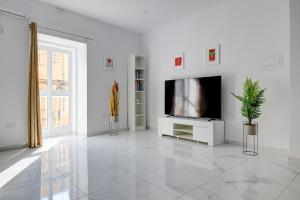 una sala de estar blanca con TV y una planta en Modern Family Holiday Retreat in Gzira, en Sliema