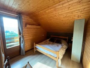 Cette chambre en bois comprend un petit lit et une fenêtre. dans l'établissement Chalet Les Sapins sauna au pied des pistes, à La Bresse