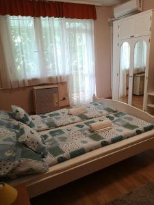 a large bed in a bedroom with a window at Natasa Apartman in Orosháza
