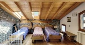 a room with two beds and a stone wall at BALLABIO LAKE - Rustic Chic Retreat in Ballabio