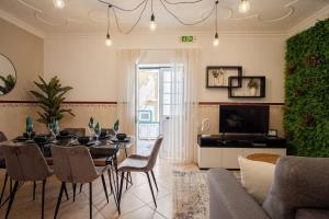 a living room with a table and chairs and a television at Milena's House in Nazaré