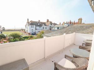 a balcony with chairs and tables on a white fence at Crabbe House in Aldeburgh