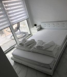 a white bed in a room with a large window at Alex Apartments Skiathos in Skiathos Town