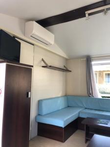 a living room with a blue couch and a tv at Mobilhome 3 chambres in Bias