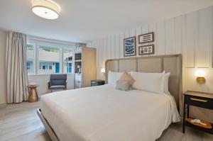- une chambre avec un grand lit blanc et une chaise dans l'établissement Greyfinch Chatham Inn, à Chatham