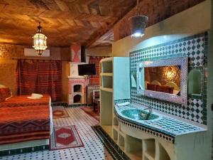 a bathroom with a sink and a bed in a room at Hotel ksar merzouga in Merzouga