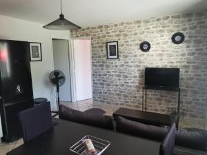 a living room with a brick wall and a tv at Appt proche des vignes in Perrigny-lès-Dijon