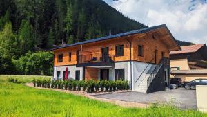 ein Backsteinhaus mit einem Balkon und einem Hof in der Unterkunft Am Römerweg - Appartements in Sankt Anton am Arlberg