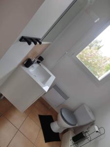 a white bathroom with a toilet and a window at Le numéro 2 in Mirepeisset
