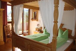 a bedroom with a canopy bed with green pillows at Neubauhof in Reith im Alpbachtal