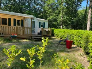 a tiny house in a yard next to a hedge at Mobil home 2 in Saint-Chéron