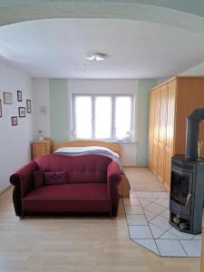 a living room with a red couch and a stove at Ferienwohnung Rosengarten in Ballenstedt +17 photos