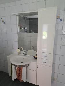 a white bathroom with a sink and a mirror at Ferienwohnung Rosengarten in Ballenstedt