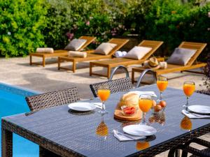 a table with a plate of food and glasses of orange juice at Almond Grove Luxury Villa Wprivate Pool in Simou
