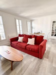 a red couch in a living room with a table at Logement entier 75 m2 in Boulogne-Billancourt
