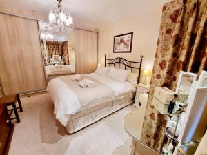 a bedroom with a large bed and a chandelier at Cosy Family Haven: Spacious 3-Bedroom Retreat in Christchurch in Iford