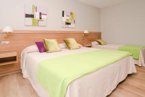 1 dormitorio con 2 camas con almohadas verdes y moradas en Hotel Caribe Sanxenxo, en Sanxenxo