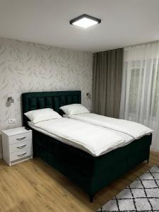 a bedroom with a large bed with a green headboard at Apartman Kosuta Lux in Tjentište