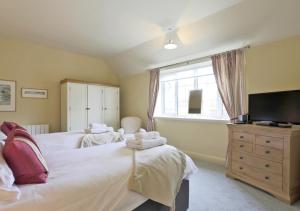 a bedroom with two beds and a flat screen tv at Wing Cottage in Orford
