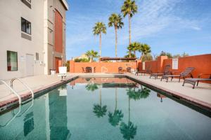 una piscina con sillas y palmeras junto a un edificio en Holiday Inn Express & Suites Tucson North, Marana, an IHG Hotel, en Tucson