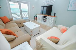 a living room with couches and a flat screen tv at Sea Coast Gardens II 401 in New Smyrna Beach