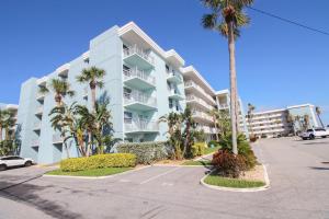 un grand immeuble avec des palmiers et un parking dans l'établissement Sea Coast Gardens II 401, à New Smyrna Beach