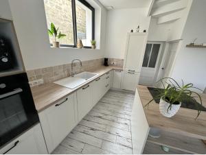 uma cozinha com armários brancos e um lavatório em Jolie maison ételoise - mer , cœur d etel em Étel