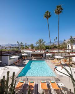 uma piscina num resort com cadeiras e palmeiras em Del Marcos Hotel, A Kirkwood Collection Hotel em Palm Springs